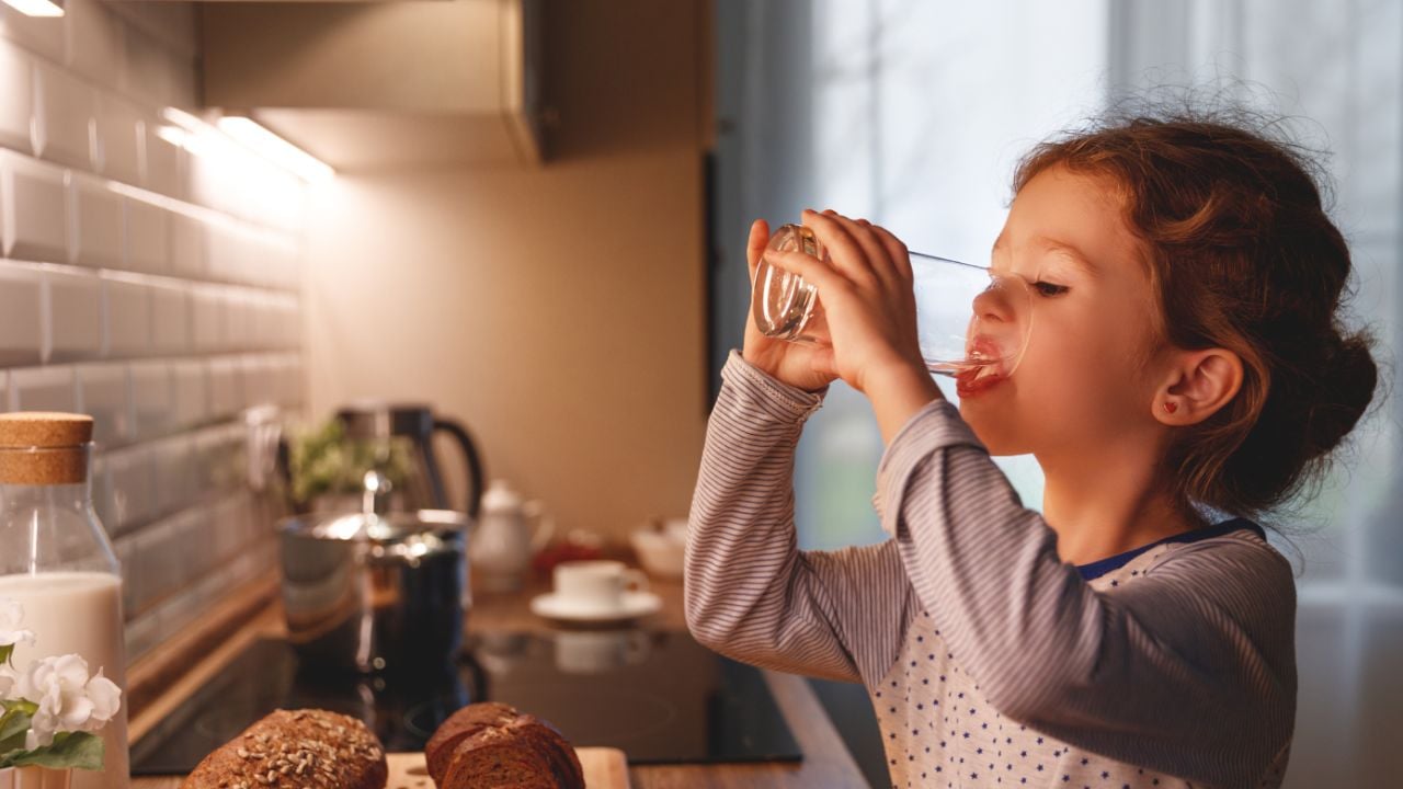 Girl drinking a glass of water in the kitchen